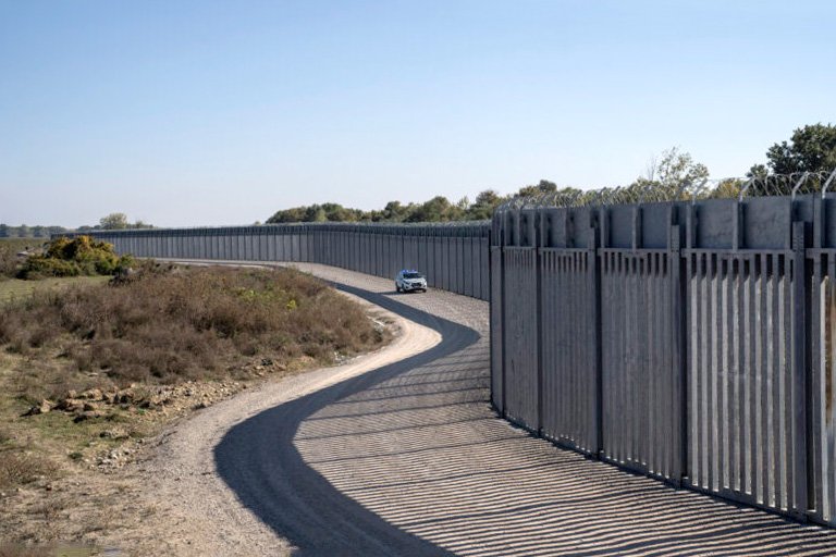 Security car on patrol along heavy-duty solid fence