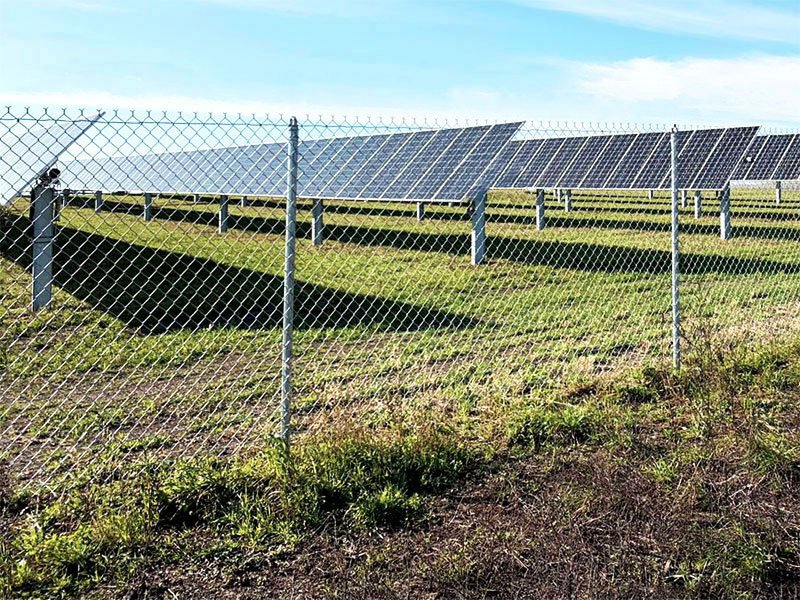 Solar panel strings viewed from behind the fence - OPTIFENCE perimeter security system is exceptionally suitable for use in solar power plants