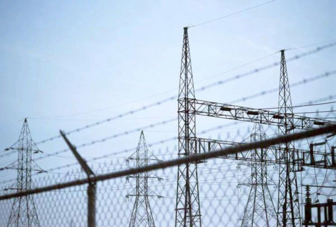 Electrical transmission towers view behind chain-link fence