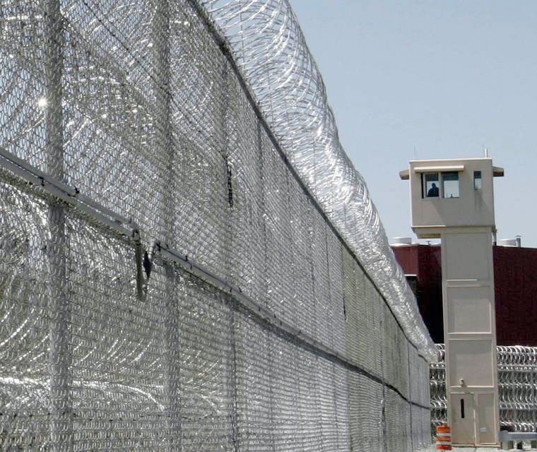 Dense chain-link fence and razor concertina on top at correctional facility