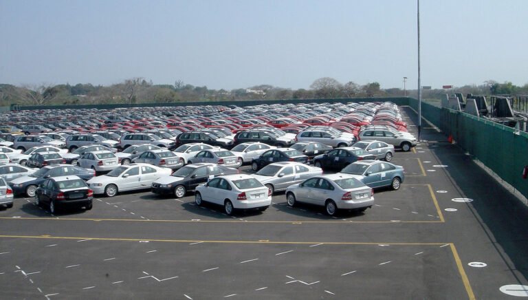 Passenger cars parked in outdoor fenced dealership lot