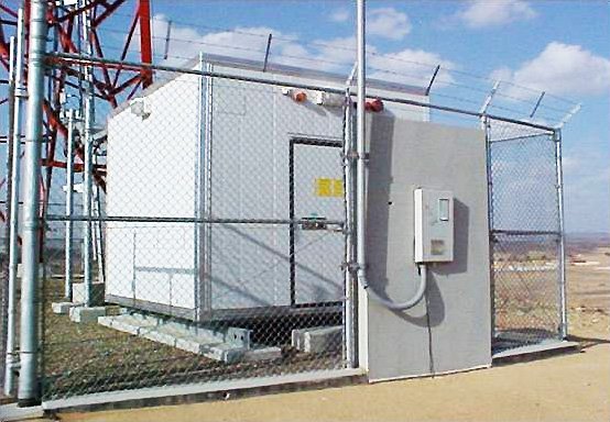 Rural mobile telephony base station surrounded by chain-link fence